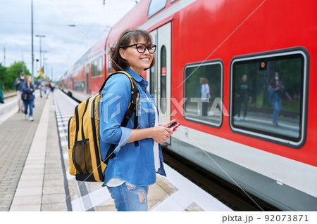 Woman passenger waiting for commuter train at station outdoor platform 92073871