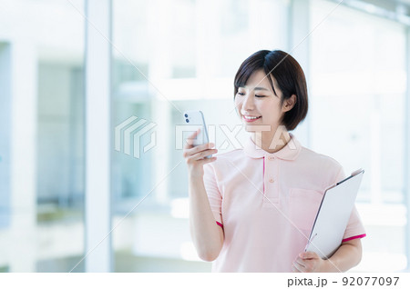 スマートフォンを使う若い女性介護士 92077097