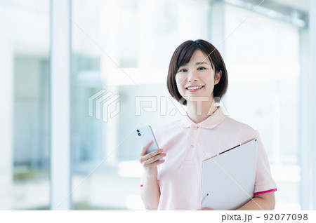 スマートフォンを使う若い女性介護士 92077098