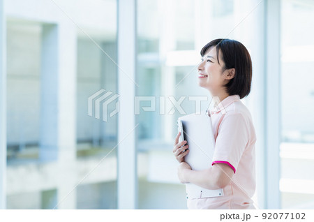 スマートフォンを使う若い女性介護士 スマートフォンを使う若い女性介護士 92077102