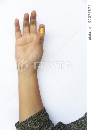 Female hand picking one pill isolated on white background with customizable space for text or ideas. 92077374