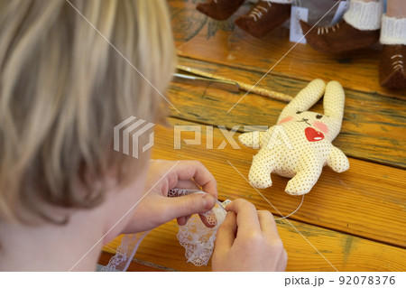 The child made a soft toy - a hare. The girl straightens her skirt on a toy. Easter Bunny. Handmade. Handmade soft toy 92078376