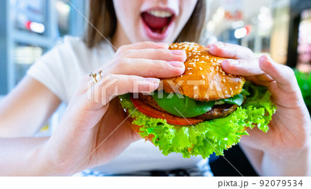 Hamburger vegan healthy vegetarian burger. Salad, avocado, vegetable on veggie sandwich eating cute woman. Tasty vegetarian healthy green food. Hamburger vegan healthy vegetarian burger. Salad, avocado, vegetable on veggie sandwich eating cute woman. Tasty vegetarian healthy green food. 92079534