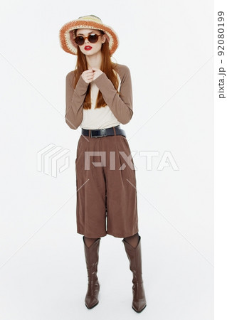 A full-length shot of a fashionable lady in a hat and glasses posing in motion on a white background in the studio. Cool banner for designers 92080199