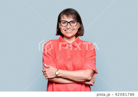 Portrait of mid adult woman in red dress looking at camera on gray isolated background 92081786