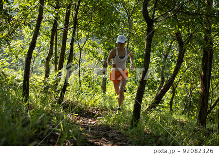Woman runner running on forest trail Woman runner running on forest trail 92082326