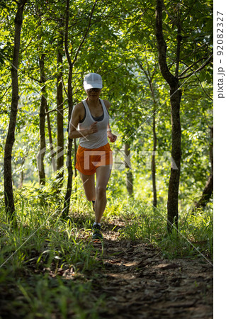 Woman runner running on forest trail. Woman runner running on forest trail. 92082327