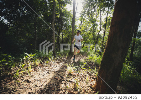 Trail runner running in summer forest trail. 92082455