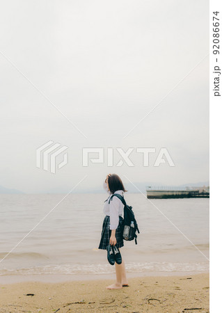 制服姿の女子高生と綺麗な海岸風景 92086674