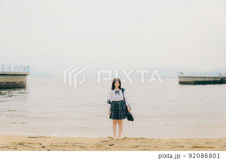 制服姿の女子高生と綺麗な海岸風景 92086801