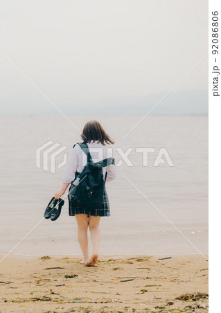 制服姿の女子高生と綺麗な海岸風景 92086806