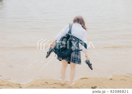 制服姿の女子高生と綺麗な海岸風景 92086821