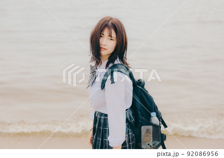 制服姿の女子高生と綺麗な海岸風景 92086956