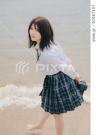 制服姿の女子高生と綺麗な海岸風景 92087107
