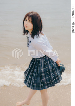 制服姿の女子高生と綺麗な海岸風景 92087108