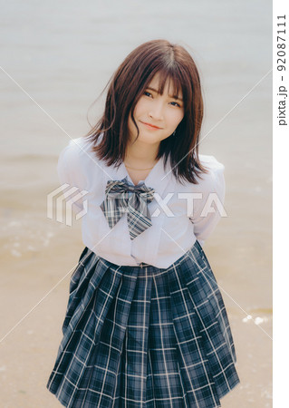 制服姿の女子高生と綺麗な海岸風景 92087111