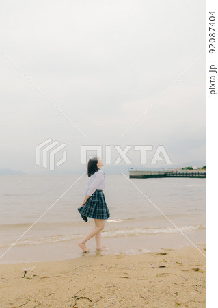 制服姿の女子高生と綺麗な海岸風景 92087404