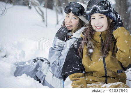 雪の降るスキー場でポーズをするスノボ女子　女子旅 92087646