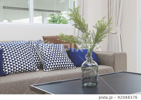 Blue glass vase with tree branches on table in living room. 92088376