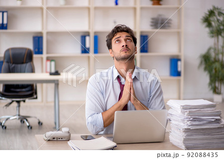 Young male employee and too much work in the office 92088435