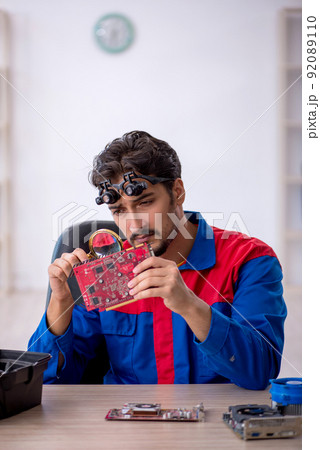 Young male repairman repairing computer Young male repairman repairing computer 92089110