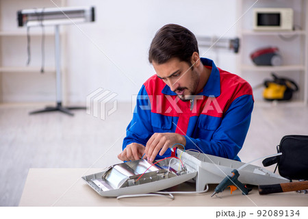 Young male repairman repairing heater 92089134