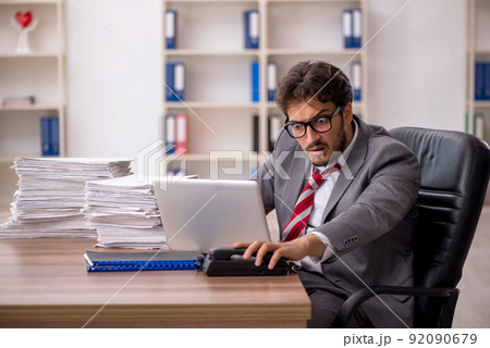 Young male employee unhappy with excessive work in the office Young male employee unhappy with excessive work in the office 92090679