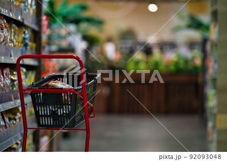 スーパーマーケットで陳列されたスイカなどの果物や日用品、赤いショッピングカート 92093048
