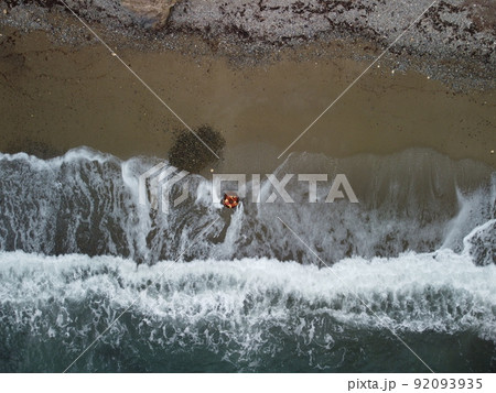 Aerial view from above on old rusty floating marine mine on the beach and volcanic rocky shores. Small waves on water surface in motion blur. Nature summer ocean sea beach background. Nobody. Aerial view from above on old rusty floating marine mine on the beach and volcanic rocky shores. Small waves on water surface in motion blur. Nature summer ocean sea beach background. Nobody. 92093935