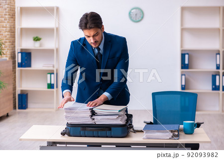 Young male employee preparing for business trip at workplace Young male employee preparing for business trip at workplace 92093982