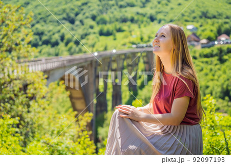 Montenegro. Woman tourist in background of Dzhurdzhevich Bridge Over The River Tara. Travel around Montenegro concept. Sights of Montenegro Montenegro. Woman tourist in background of Dzhurdzhevich Bridge Over The River Tara. Travel around Montenegro concept. Sights of Montenegro 92097193