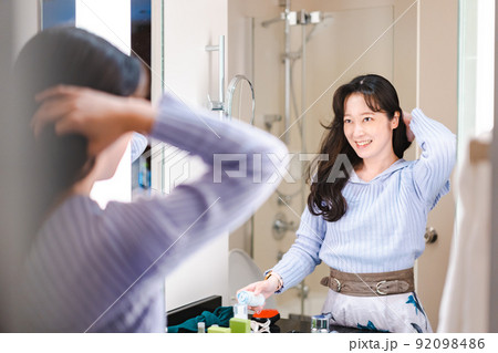鏡の前で髪のセットをする若い女性 鏡の前で髪のセットをする若い女性 92098486