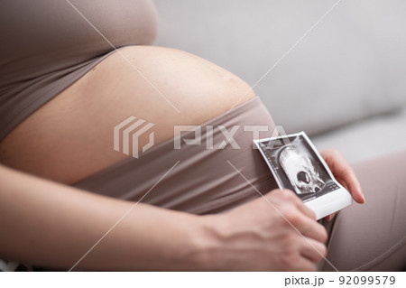 Pregnant woman belly. Pregnancy Concept. Pregnant tummy close up. Detail of pregnant woman relaxing on comfortable sofa at home. Pregnant woman belly. Pregnancy Concept. Pregnant tummy close up. Detail of pregnant woman relaxing on comfortable sofa at home. 92099579