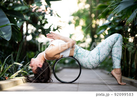 Female meditating and practicing yoga in tropical rainforest. Beautiful young woman practicing yoga outdoor with tropical forest in background. Female meditating and practicing yoga in tropical rainforest. Beautiful young woman practicing yoga outdoor with tropical forest in background. 92099583