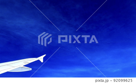 飛行機の翼とかすみ雲がかかる青空 92099625