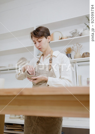 woman ceramist in the workshop makes mugs out of clay. small business or hobby is the creation of ceramic products woman ceramist in the workshop makes mugs out of clay. small business or hobby is the creation of ceramic products 92099784