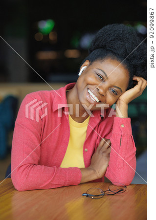 portrait of a thoughtful African American woman in a pink shirt and glasses. a happy woman is relaxing in a public place and posing 92099867