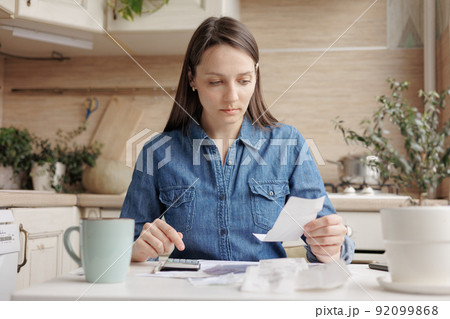 woman pays utility bills and writes checks. a European woman at home makes a calculation of expenses for a month 92099868