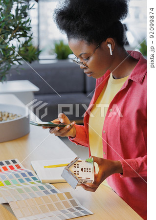 African American woman architect or designer works in a coworking office. a woman creates a residential house project and holds a mock-up  92099874