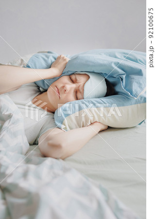 woman lies in bed and covers her head with pillows. the woman suffers from insomnia or sleep disorders woman lies in bed and covers her head with pillows. the woman suffers from insomnia or sleep disorders 92100675