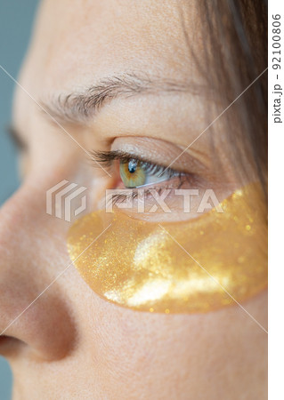 Caucasian or European woman with gold patches under her eyes cares for her skin moisturizing 92100806