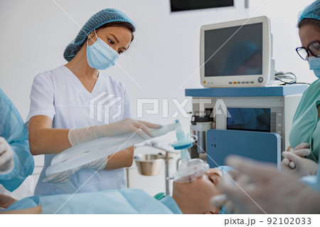 Well-trained anesthesiologist follows the patient during the surgery in clinic Well-trained anesthesiologist follows the patient during the surgery in clinic 92102033