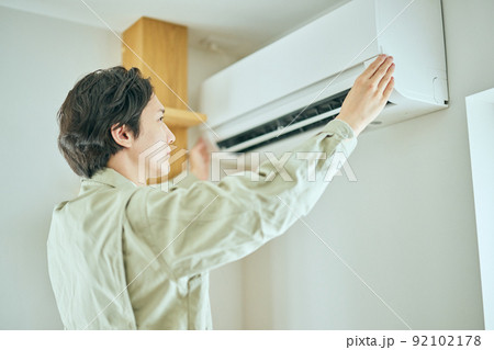 エアコンを点検する作業服姿の若い男性 エアコンを点検する作業服姿の若い男性 92102178