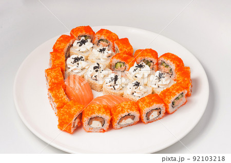 sushi rolls laid out in the shape of a heart on a white plate. Concept 92103218