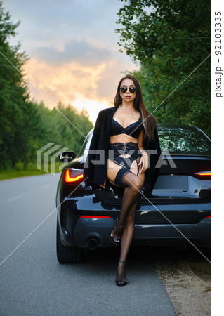 Gorgeous woman in lace lingerie and jacket over the shoulders next to the car 92103335