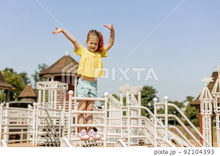 A charming little girl is having fun and playing on the playground. Happy childhood, summer time A charming little girl is having fun and playing on the playground. Happy childhood, summer time 92104393