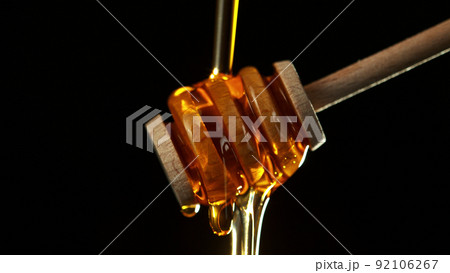 Honey dripping from wooden dripper. Honey dripping from wooden dripper. 92106267