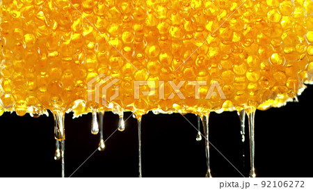 Honey dripping from honey comb on black background. Honey dripping from honey comb on black background. 92106272