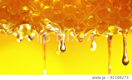 Honey dripping from honey comb on golden background. 92106273