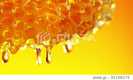 Honey dripping from honey comb on golden background. 92106275